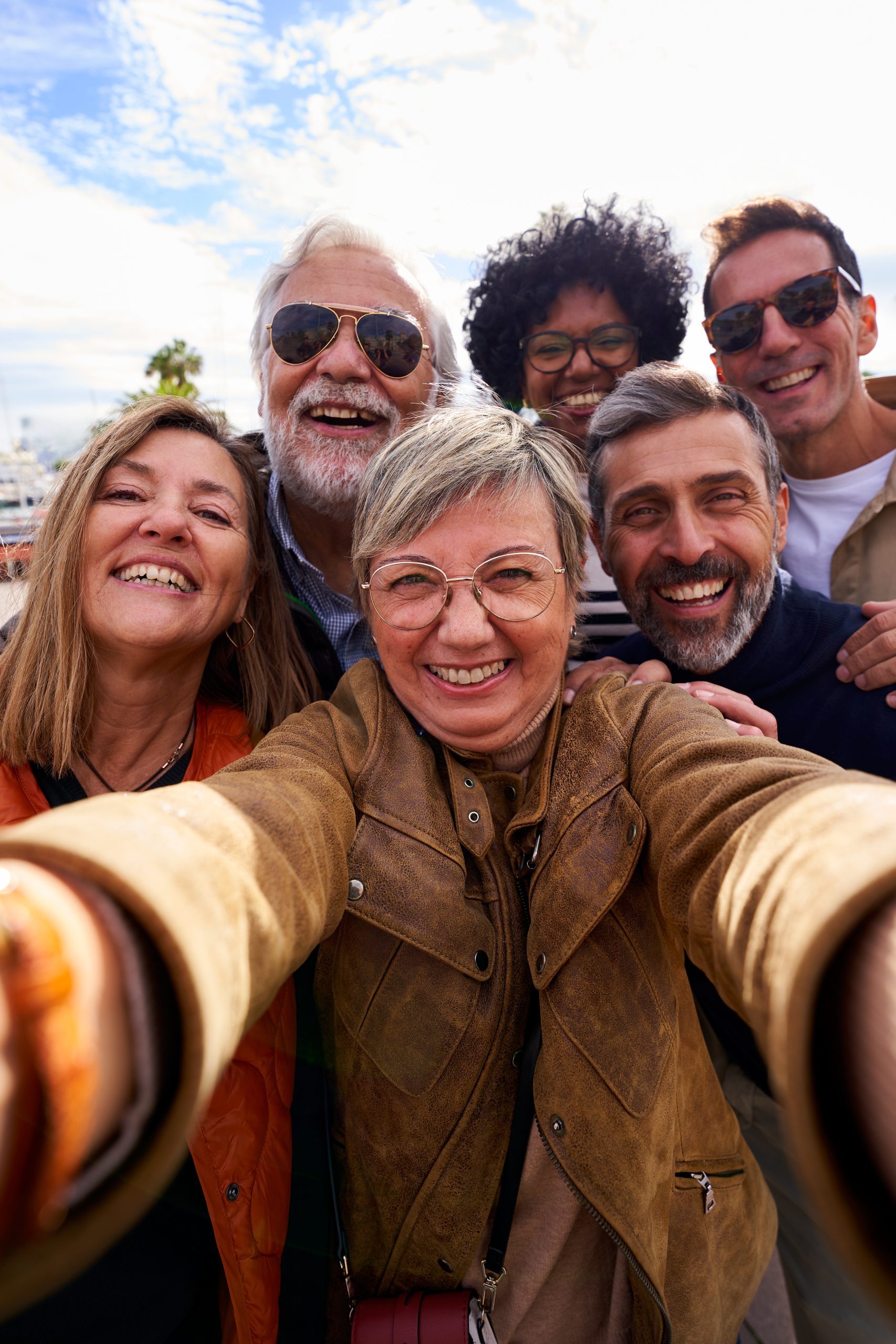Group diverse cheerful middle-aged tourist friends posing smiling taking a photo selfie embracing.